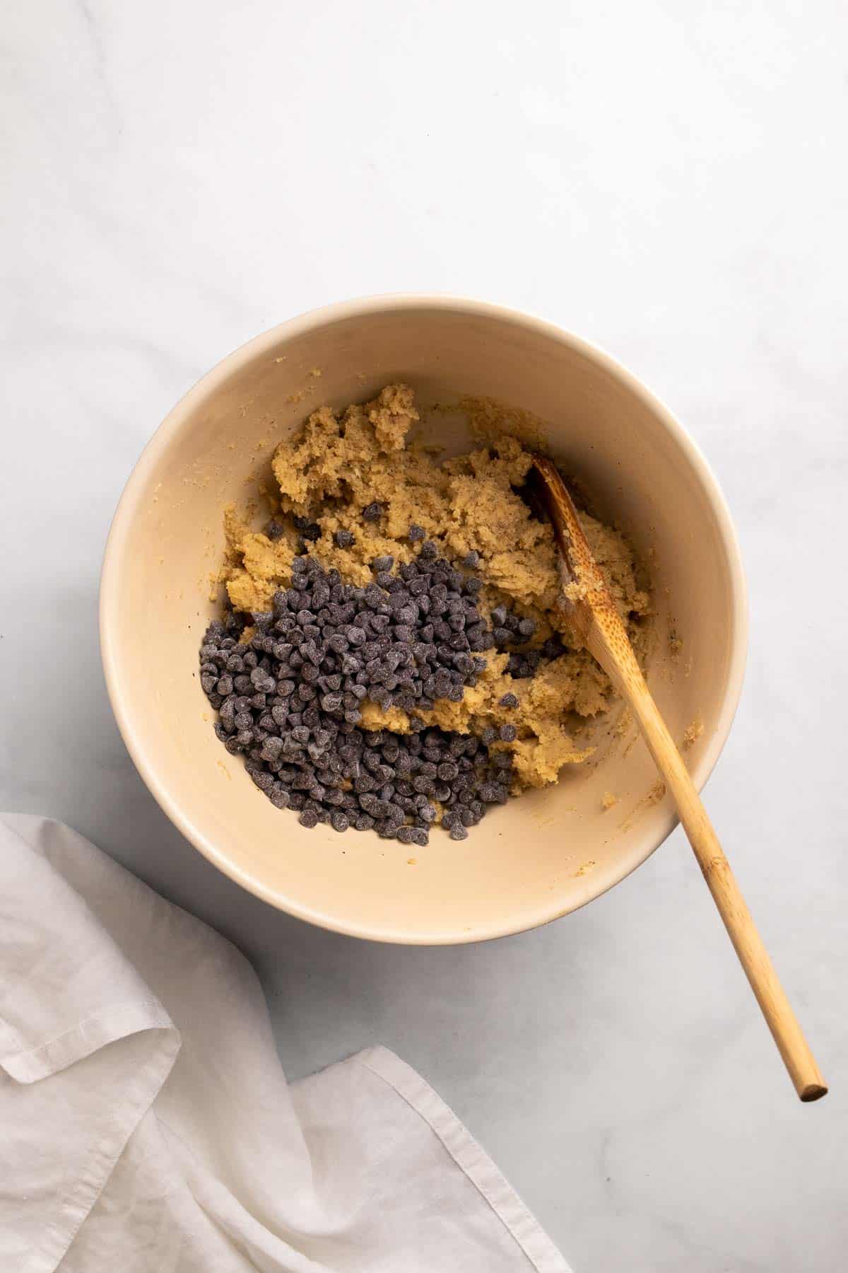 Chocolate chips added to a bowl with the cookie dough