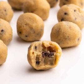 Closeup of Keto Cookie Dough balls on a white serving tray with a bite taken out of one