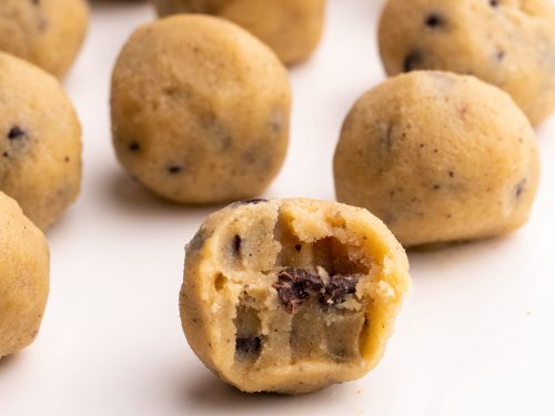 Closeup of Keto Cookie Dough balls on a white serving tray with a bite taken out of one