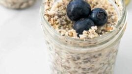 Keto overnight oats in a mason jar with three blueberries on top