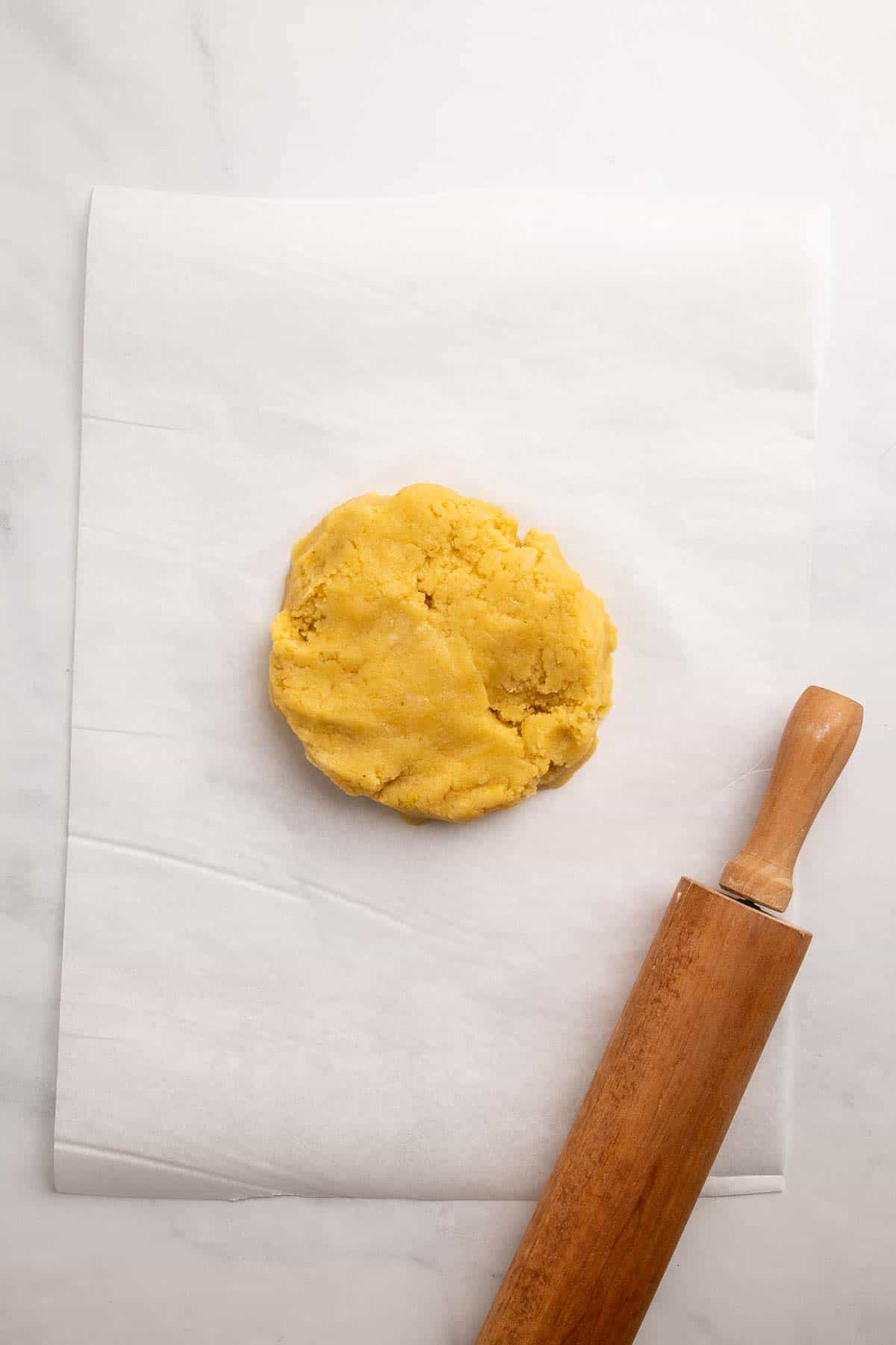 Dough flattened into a disk on a sheet of parchment paper