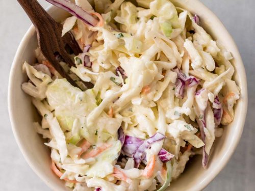 Low carb coleslaw in a white bowl with a wooden fork, as seen from above
