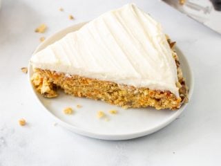 A slice of keto carrot cake on a white plate next to a serving utensil
