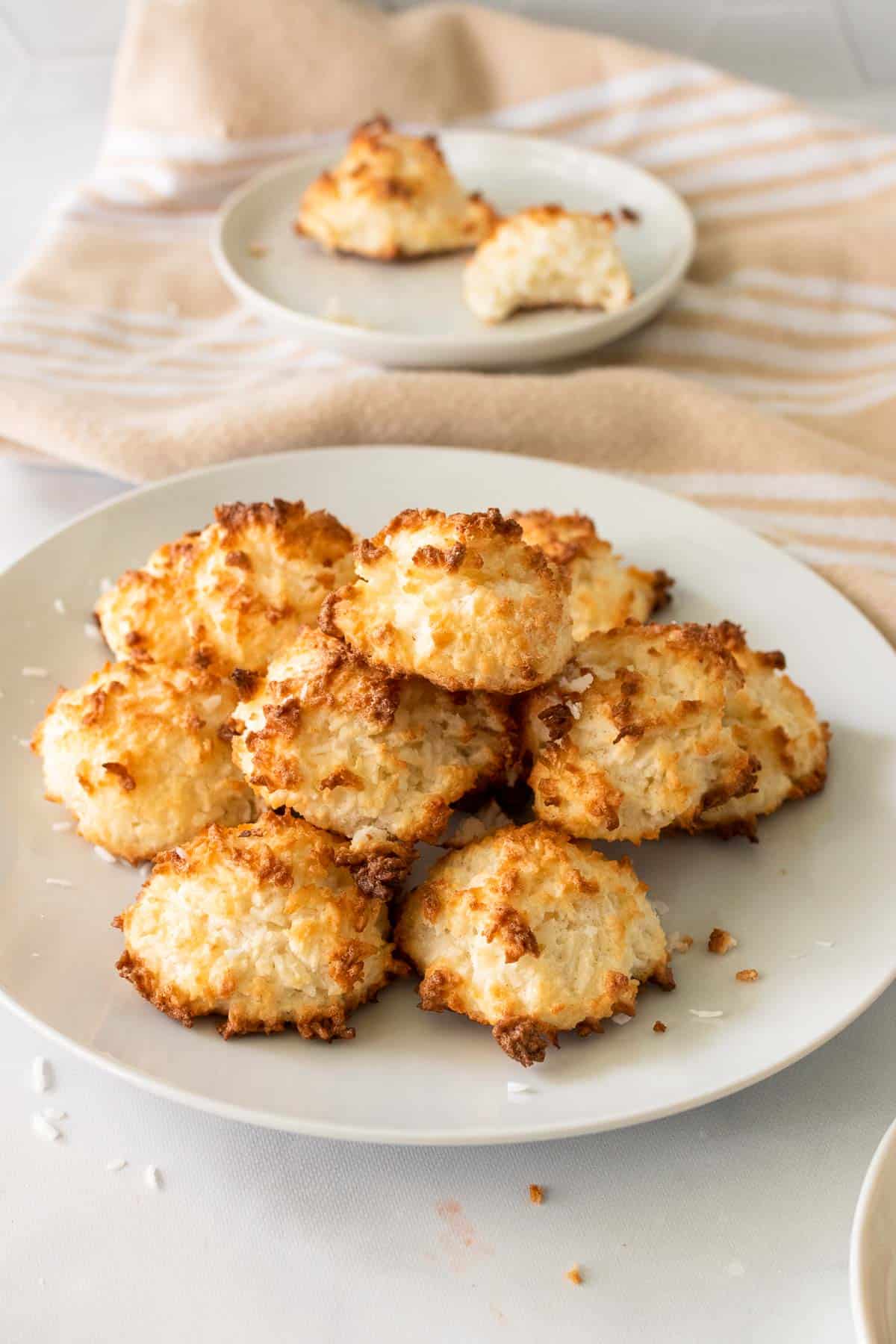 Stack of Keto Coconut Macaroons on a white plate, topped with shredded coconut