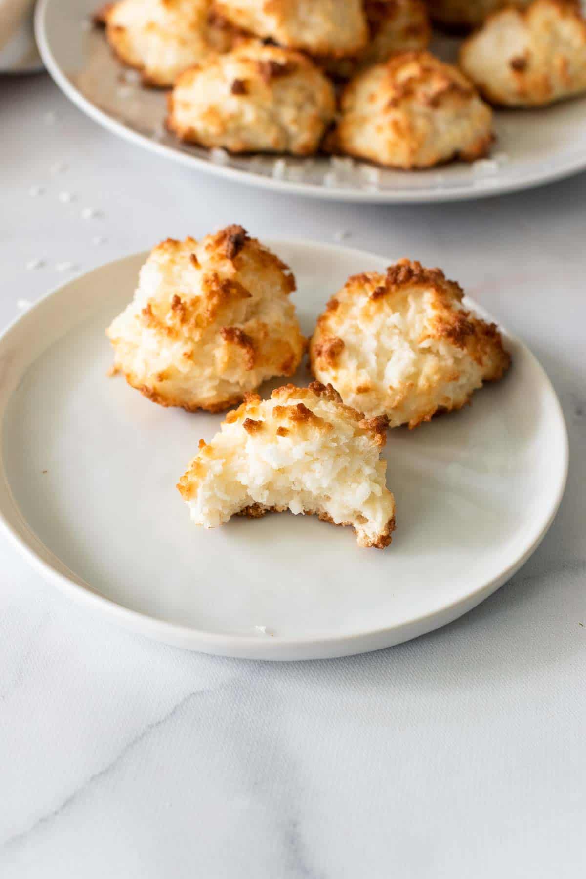 Three macaroons on a white plate with a bite taken out of one
