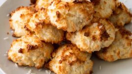 A stack of Keto Coconut Macaroons on a white plate with shredded coconut