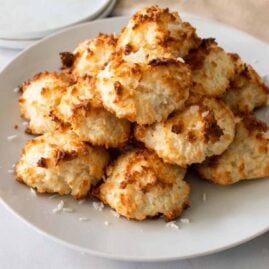 A stack of Keto Coconut Macaroons on a white plate with shredded coconut