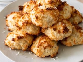 A stack of Keto Coconut Macaroons on a white plate with shredded coconut