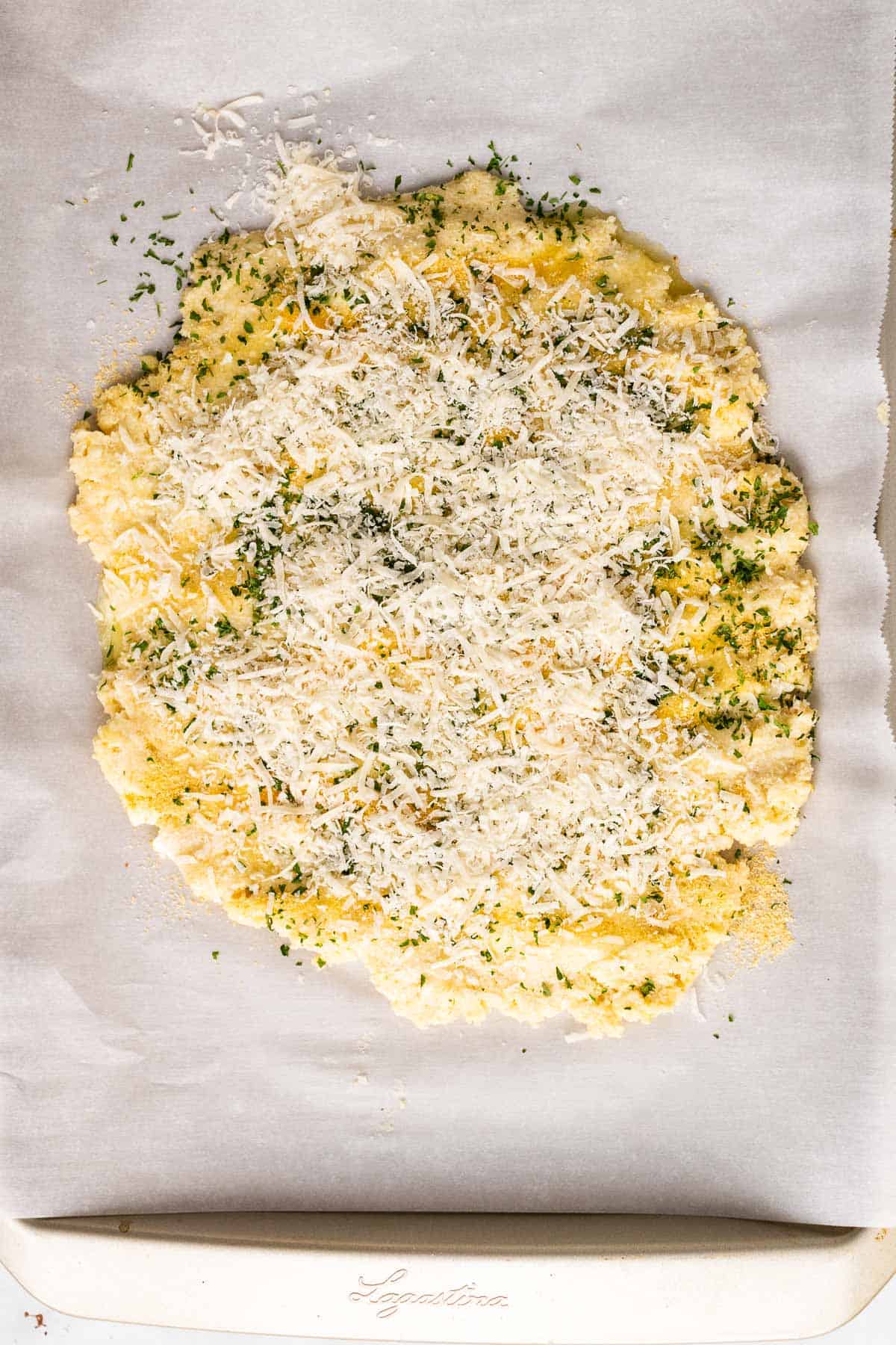 Dough topped with butter, parsley, garlic powder, salt, and Parmesan, as seen from above