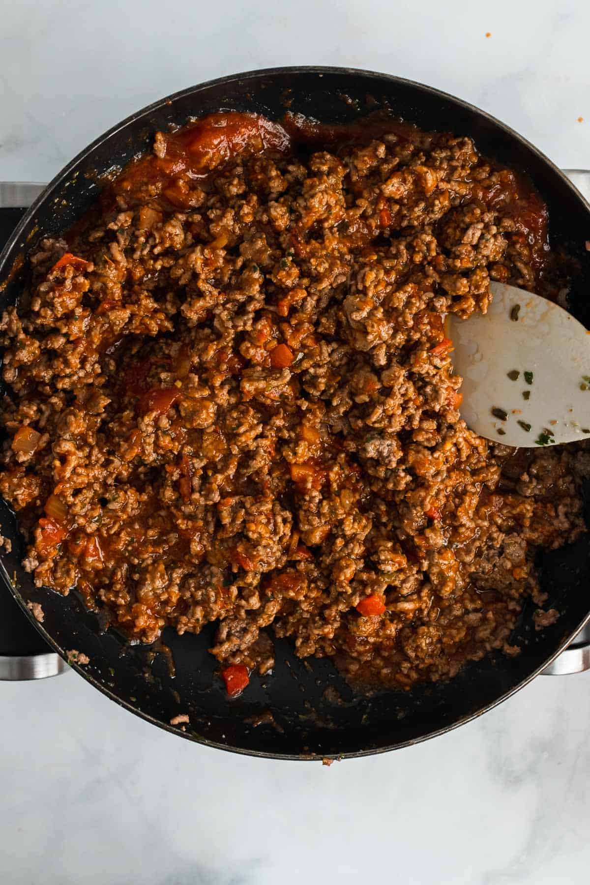 Tomato sauce stirred into the cooked ground beef in the skillet, as seen from above