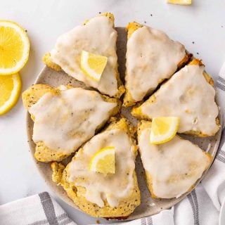 Six slices of keto scones on a serving tray topped with lemon glaze and quartered lemon slices, as seen from above