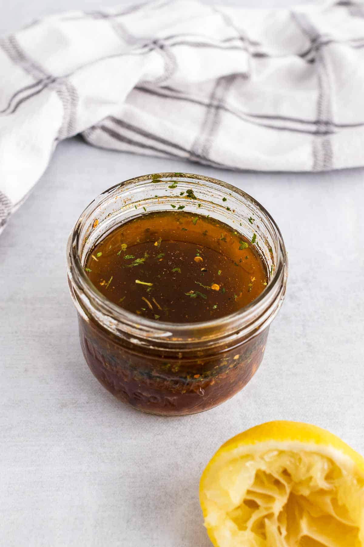 Marinade in a glass jar next to a squeezed lemon half