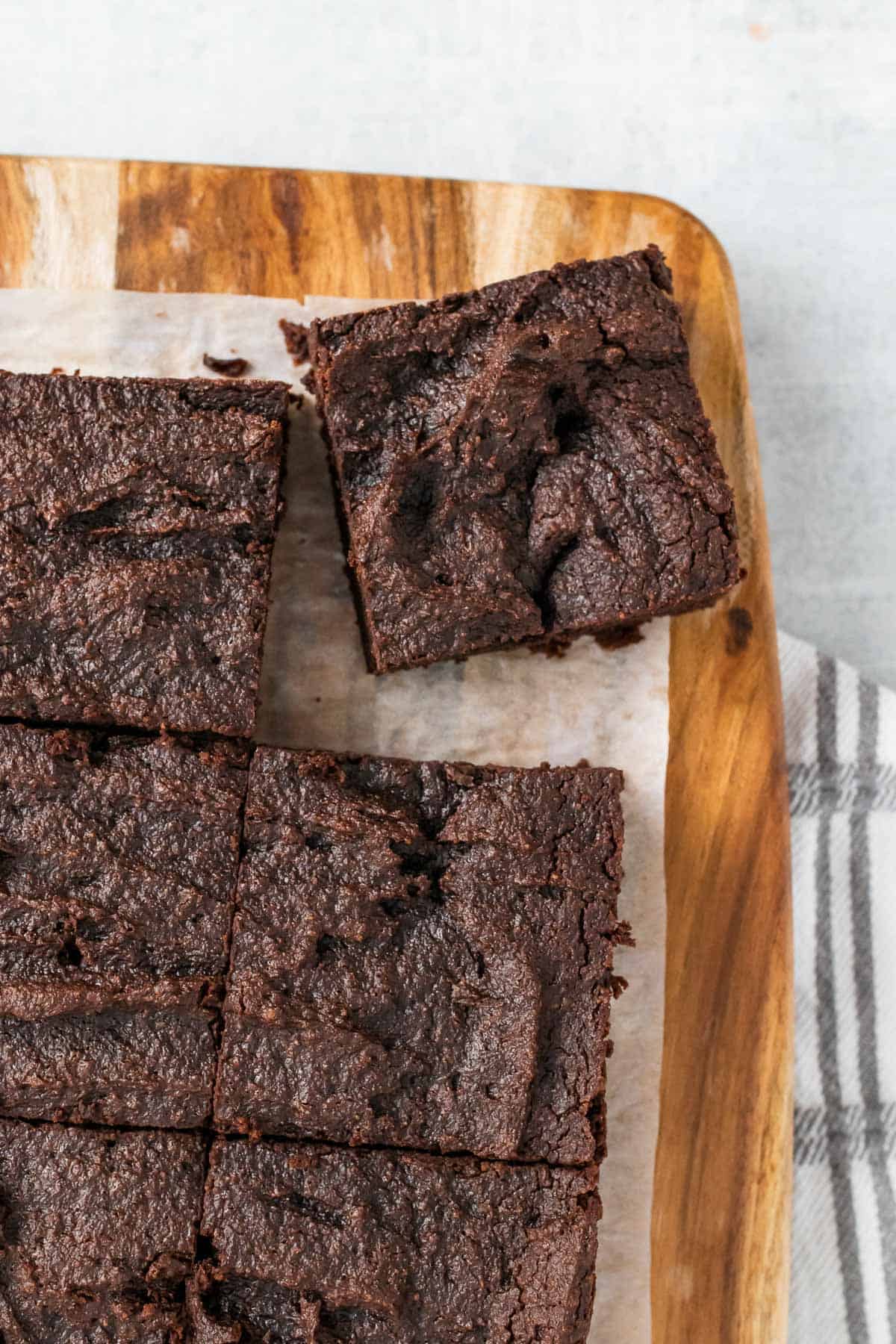 Closeup of sliced brownies on a wooden cutting board with one slice pulled slightly away from the rest