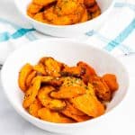 Two white bowls of roasted carrot slices