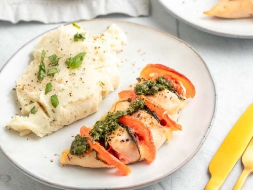 Hasselback chicken on a white plate served next to mashed potatoes