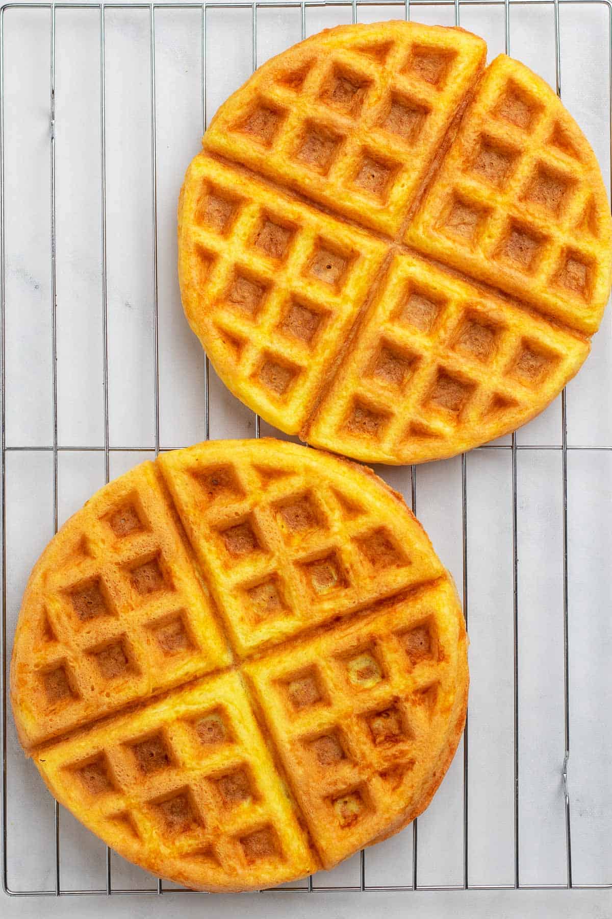 Two chaffles cooling on a wire rack, as seen from above