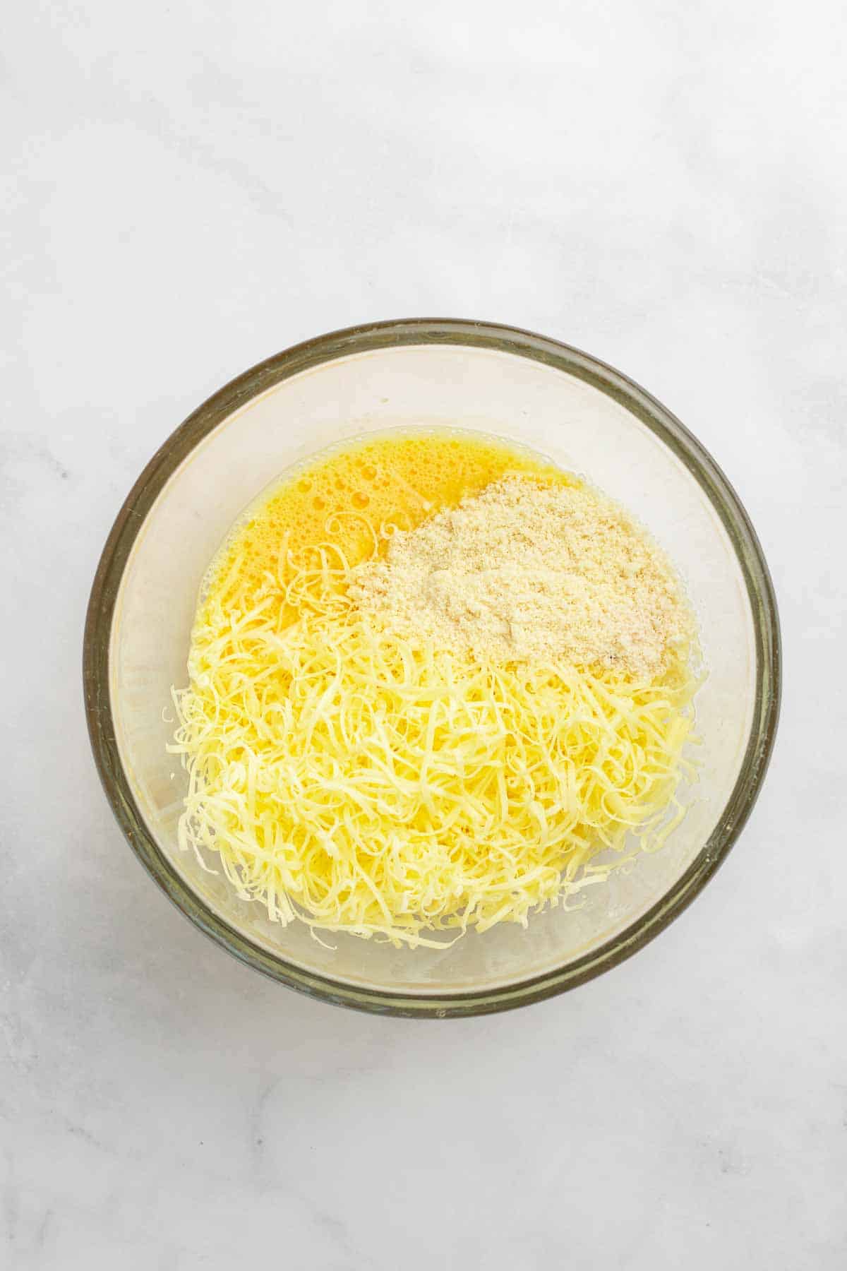 Eggs, cheese, and almond flour mixed together in a glass bowl