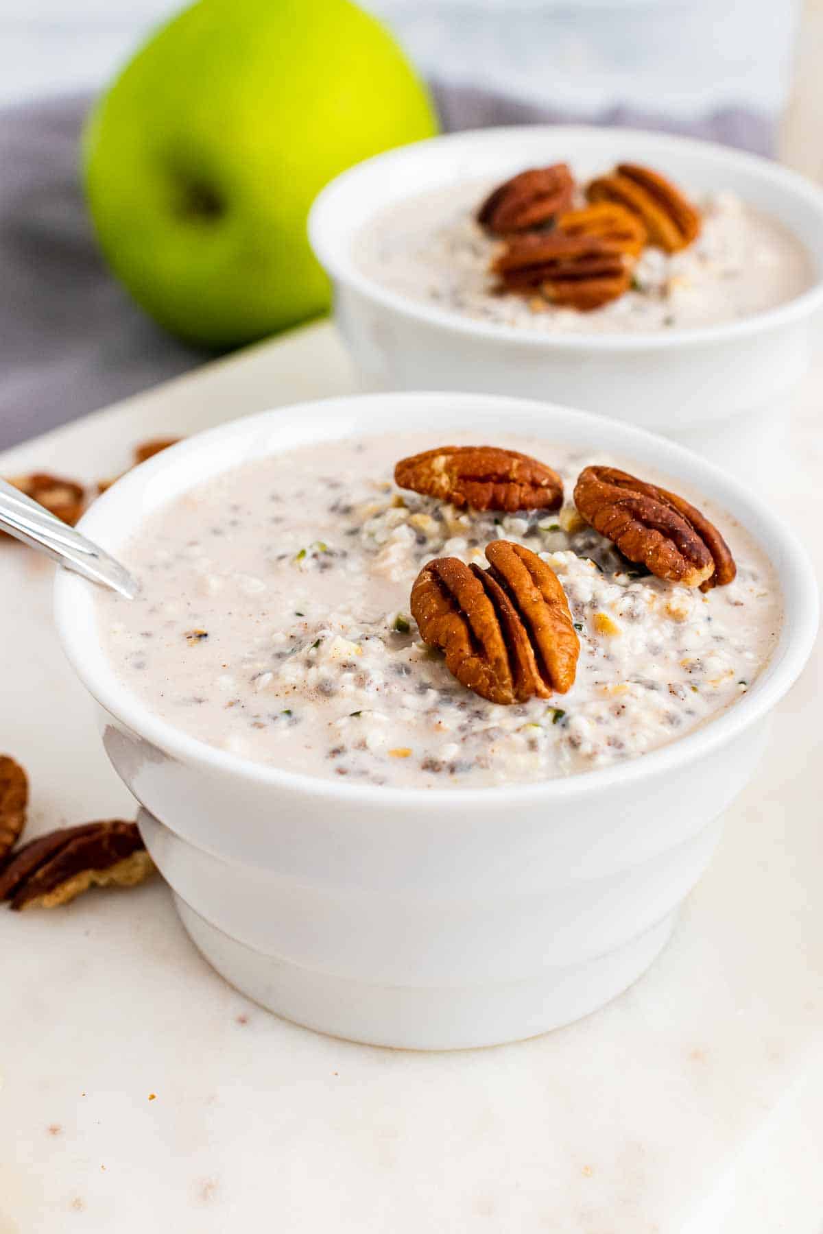 Finished oats topped with pecans in two white bowls on a white serving tray