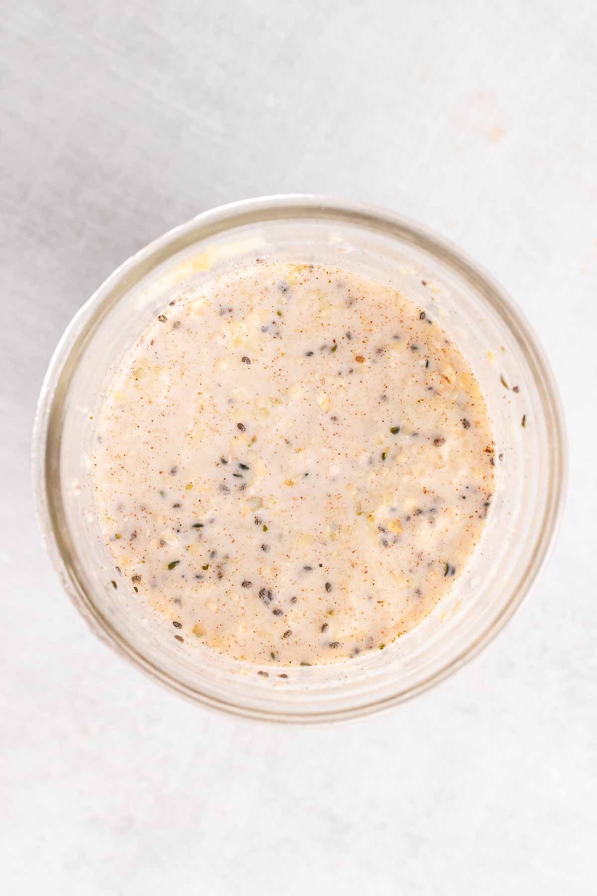 Ingredients for overnight oats mixed together in a glass jar, as seen from above