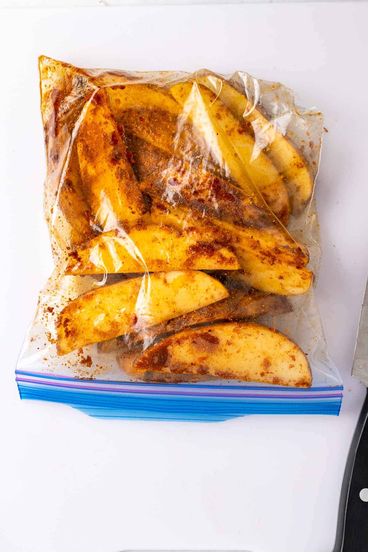 Zip-lock bag with potato wedges covered in oil and spices