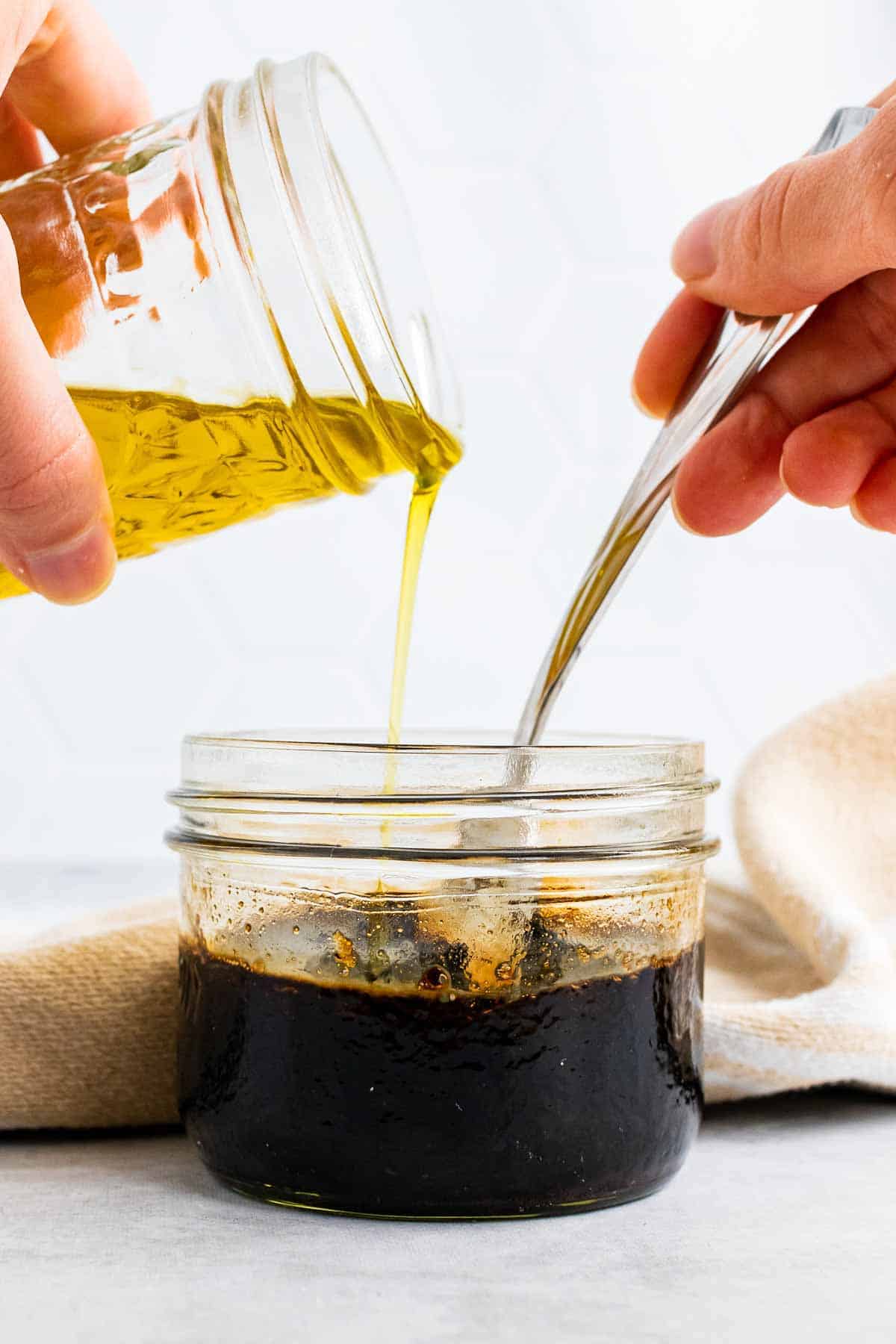 Hand pouring olive oil into glass with the other ingredients