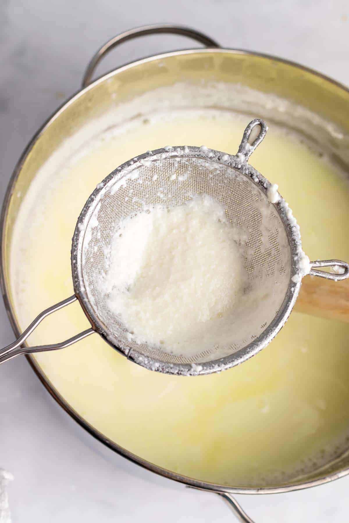 Skimmer with ricotta cheese curd over a pot