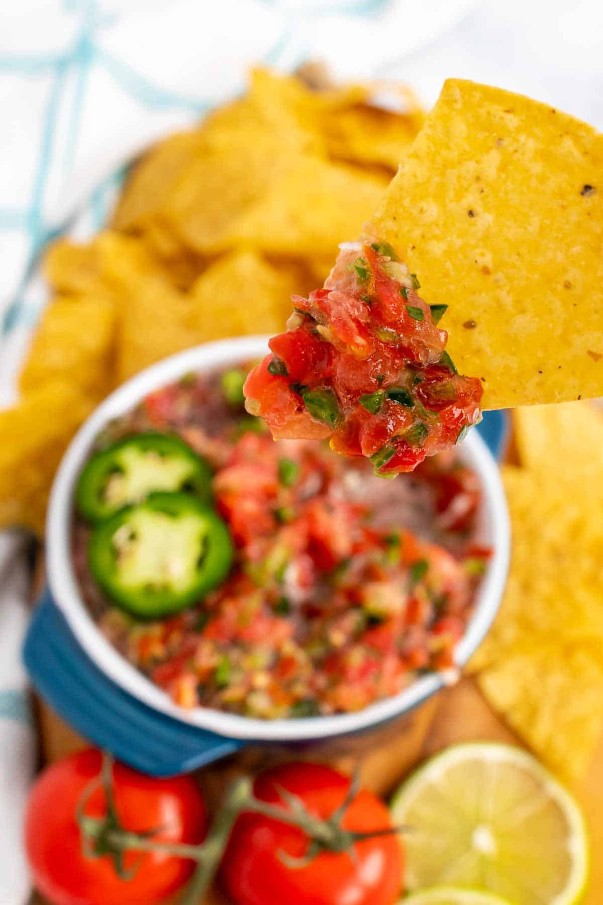 Chip with salsa over a bowl of salsa