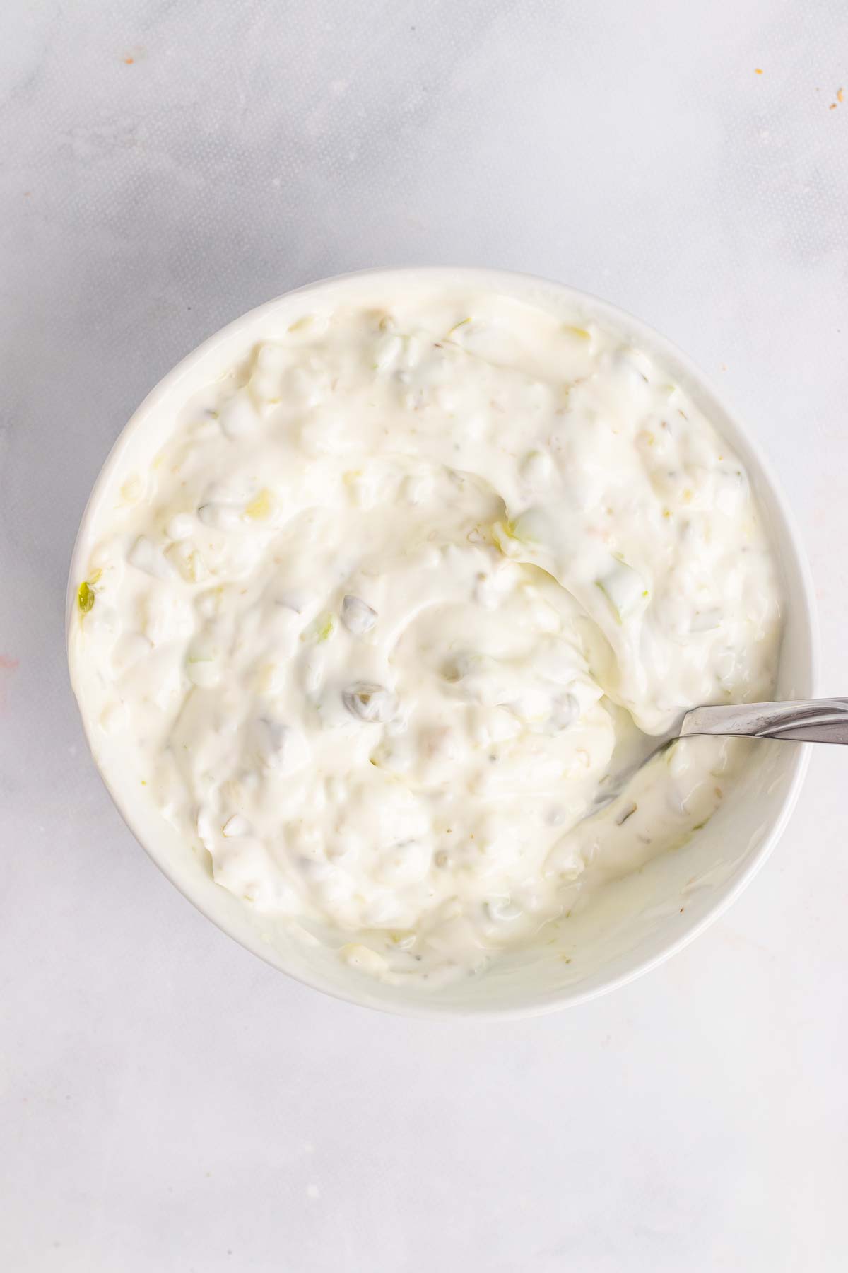 Bowl of tartar sauce with spoon on table