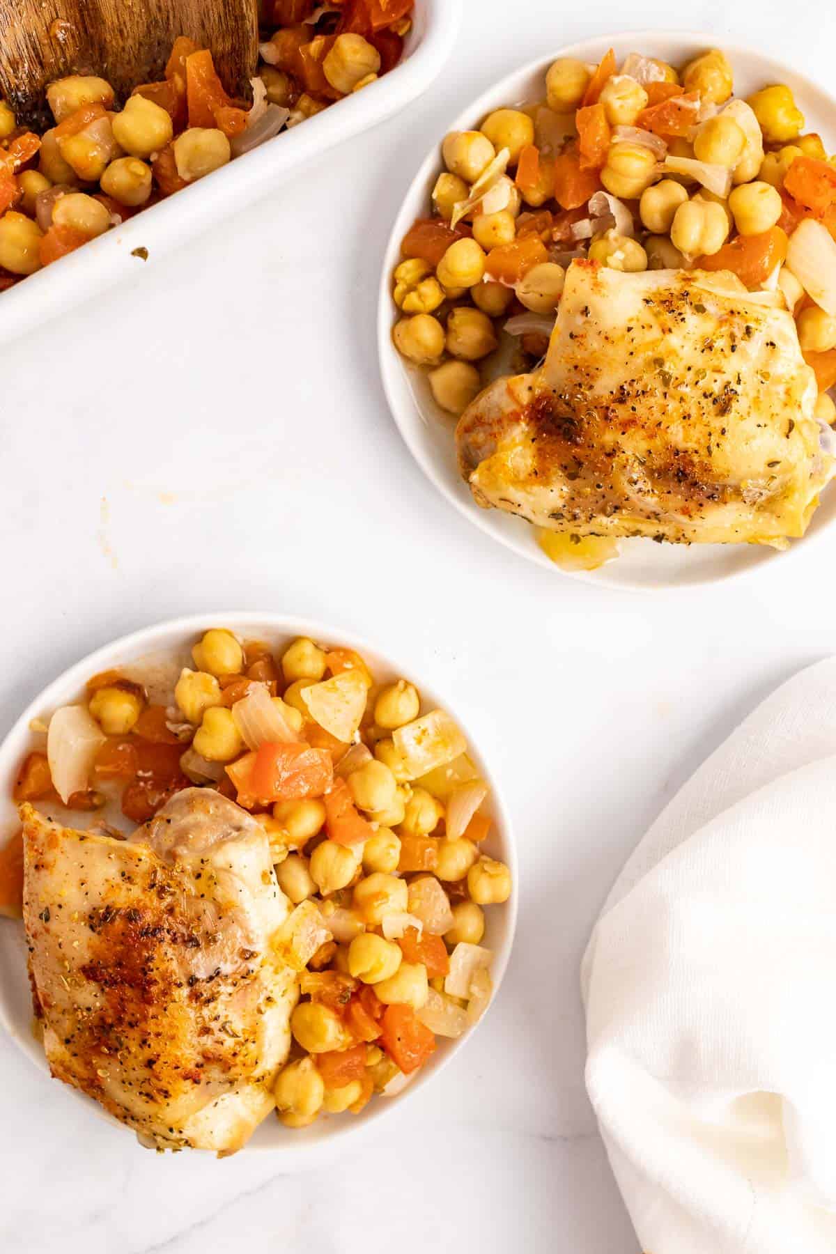 Two plates of chicken and chickpeas seen from above