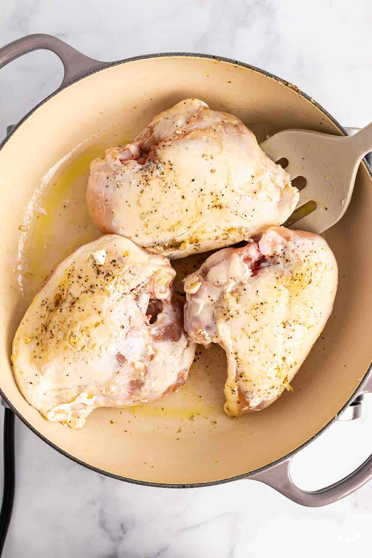 Three browned chicken breasts in pan