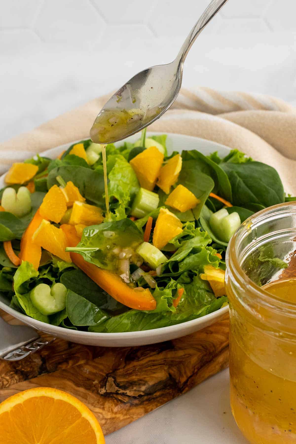Spoon drizzling vinaigrette over a spinach salad