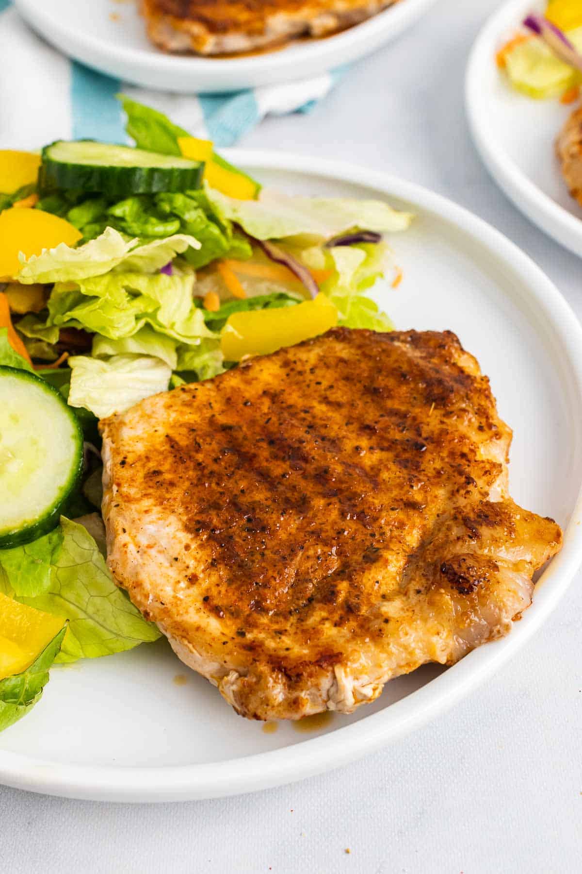 Spice-Rubbed Pork Chop on white plate with salad
