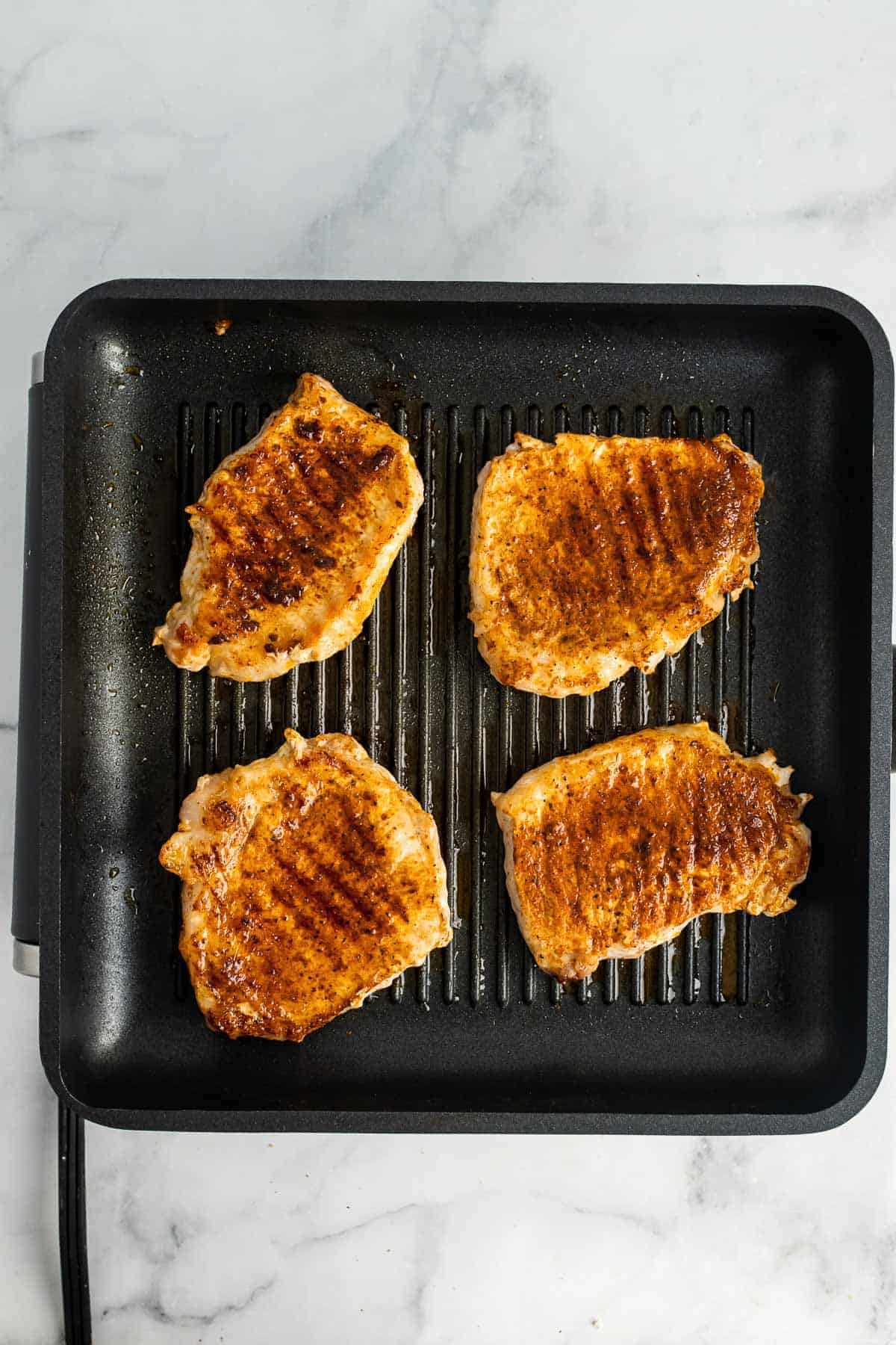 Fully cooked pork chops on a grilling pan