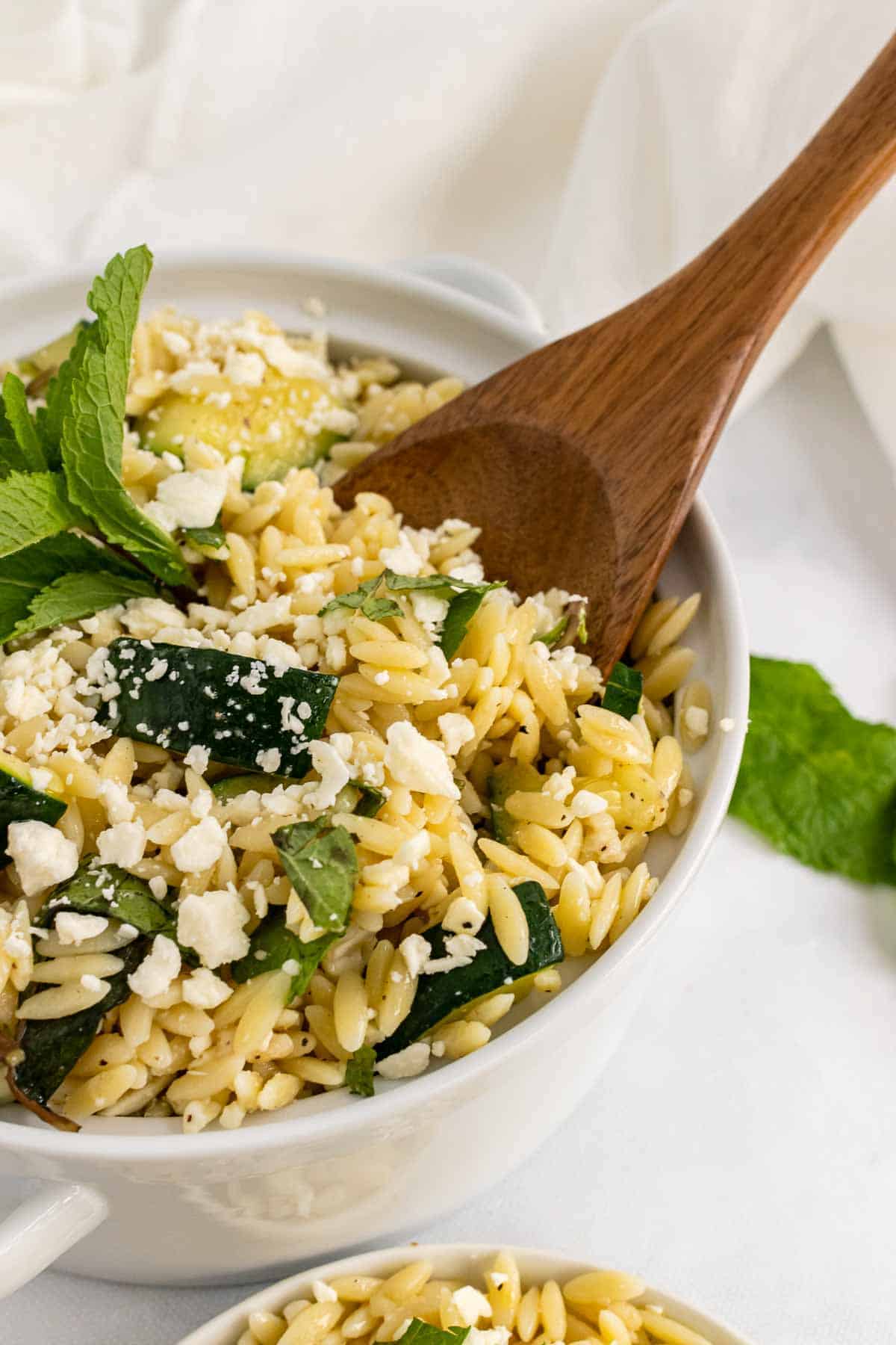 Bowl of Zucchini Orzo Salad with wooden spoon 