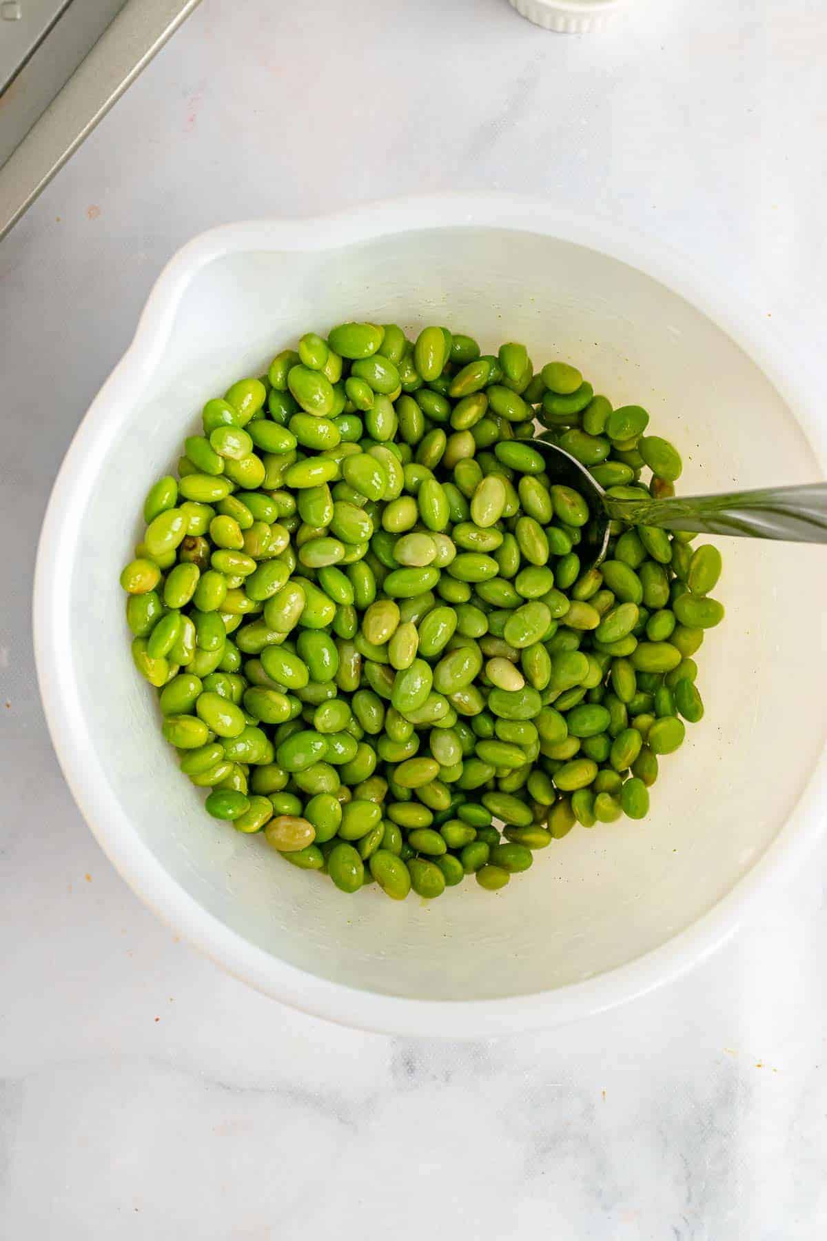 Edamame coted with wasabi in white bowl
