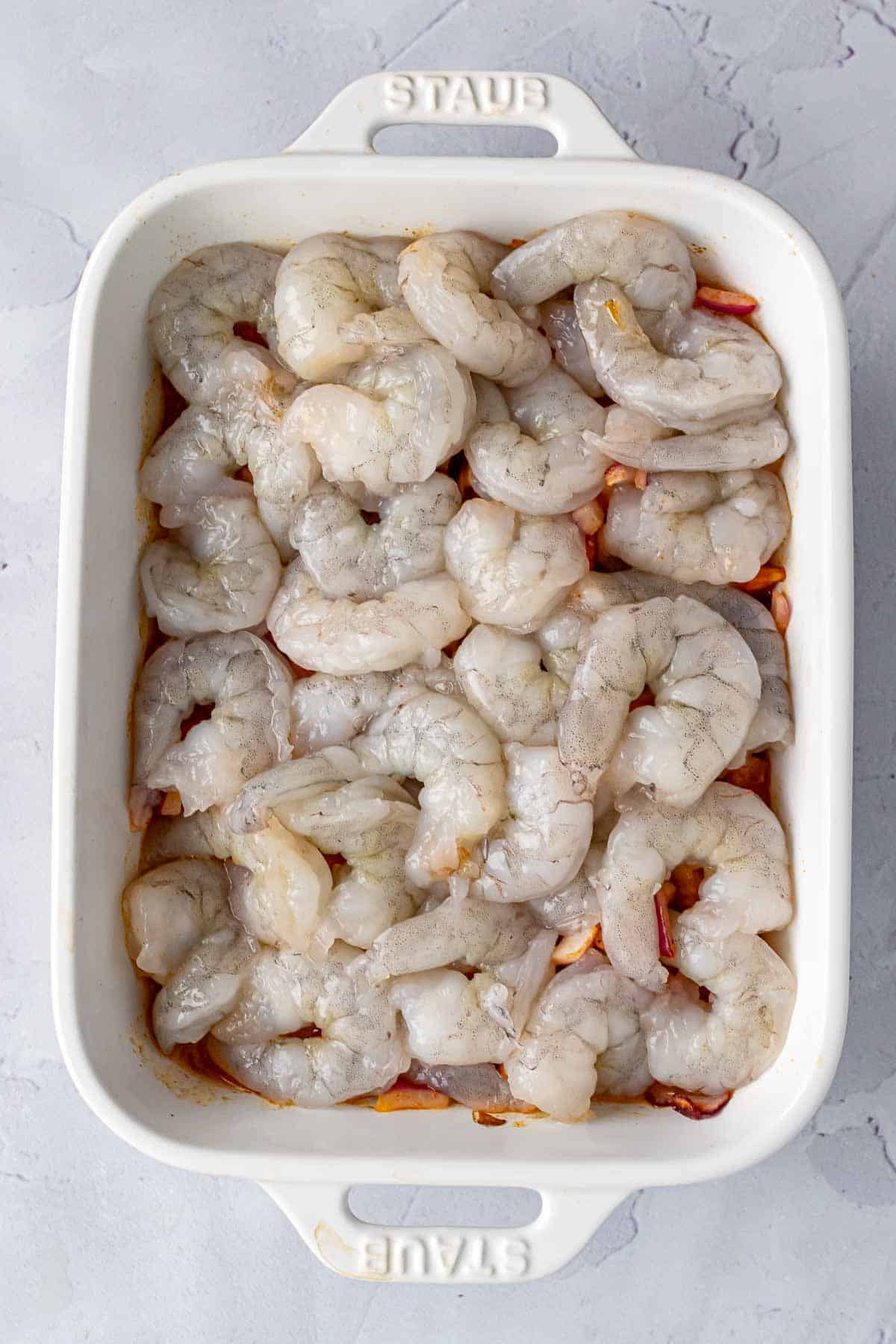 Layer of shrimp on top of the veggies in a baking dish
