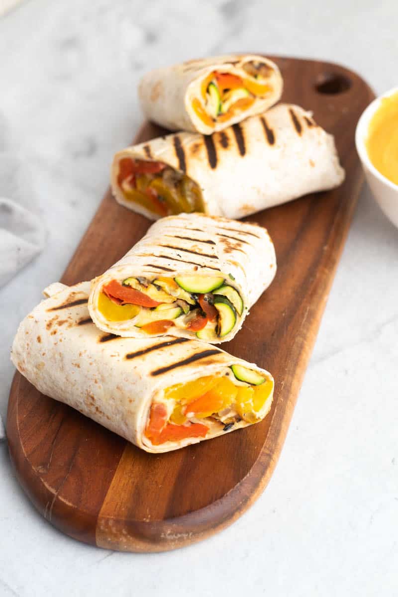 Grilled veggie wraps cut into three halves and placed on a wooden serving tray