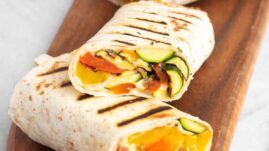 Grilled veggie wraps cut into three halves and placed on a wooden serving tray
