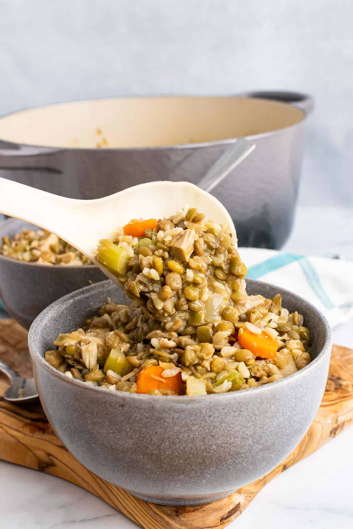 Spoonful of turkey lentil soup held above a soup bowl 