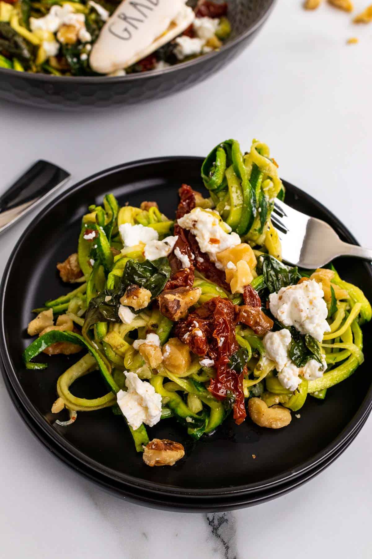 Zucchini noodles with goat cheese on a black plate