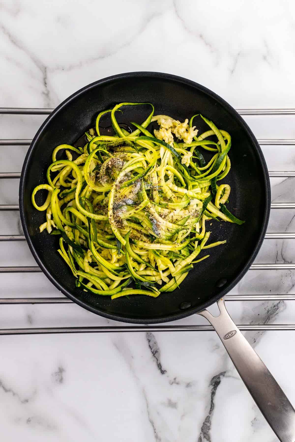 Zucchini noodles, spices, and walnuts in a pan