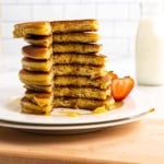 Stack of pancakes on a white plate with a quarter of the stack cut out