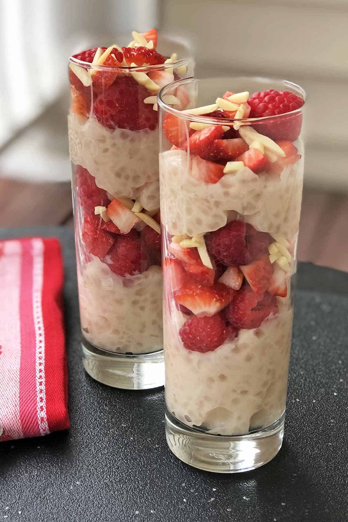 Two Tapioca Berry Parfaits in tall glasses with sliced strawberries, slivered almonds, and whole raspberries on top