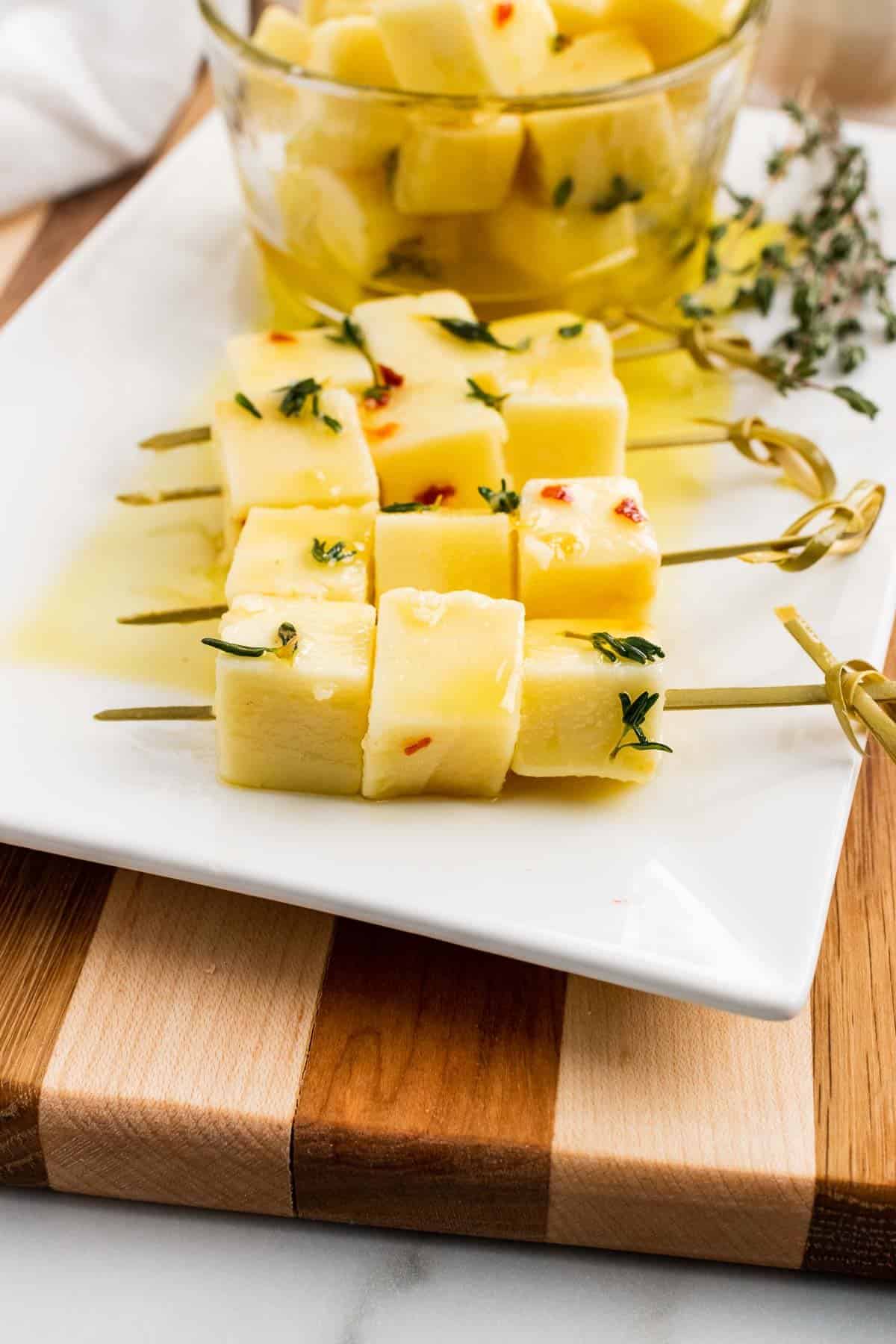 Close up of skewers with three cheese cubes on each one on a serving tray