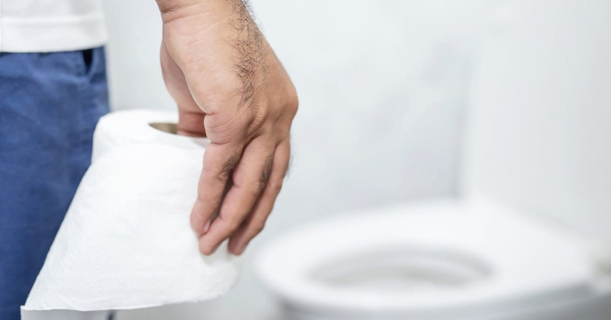 Hand holding roll of toilet paper