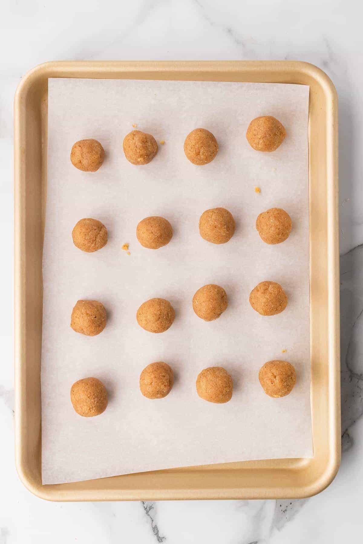 16 cookie dough balls on a baking sheet