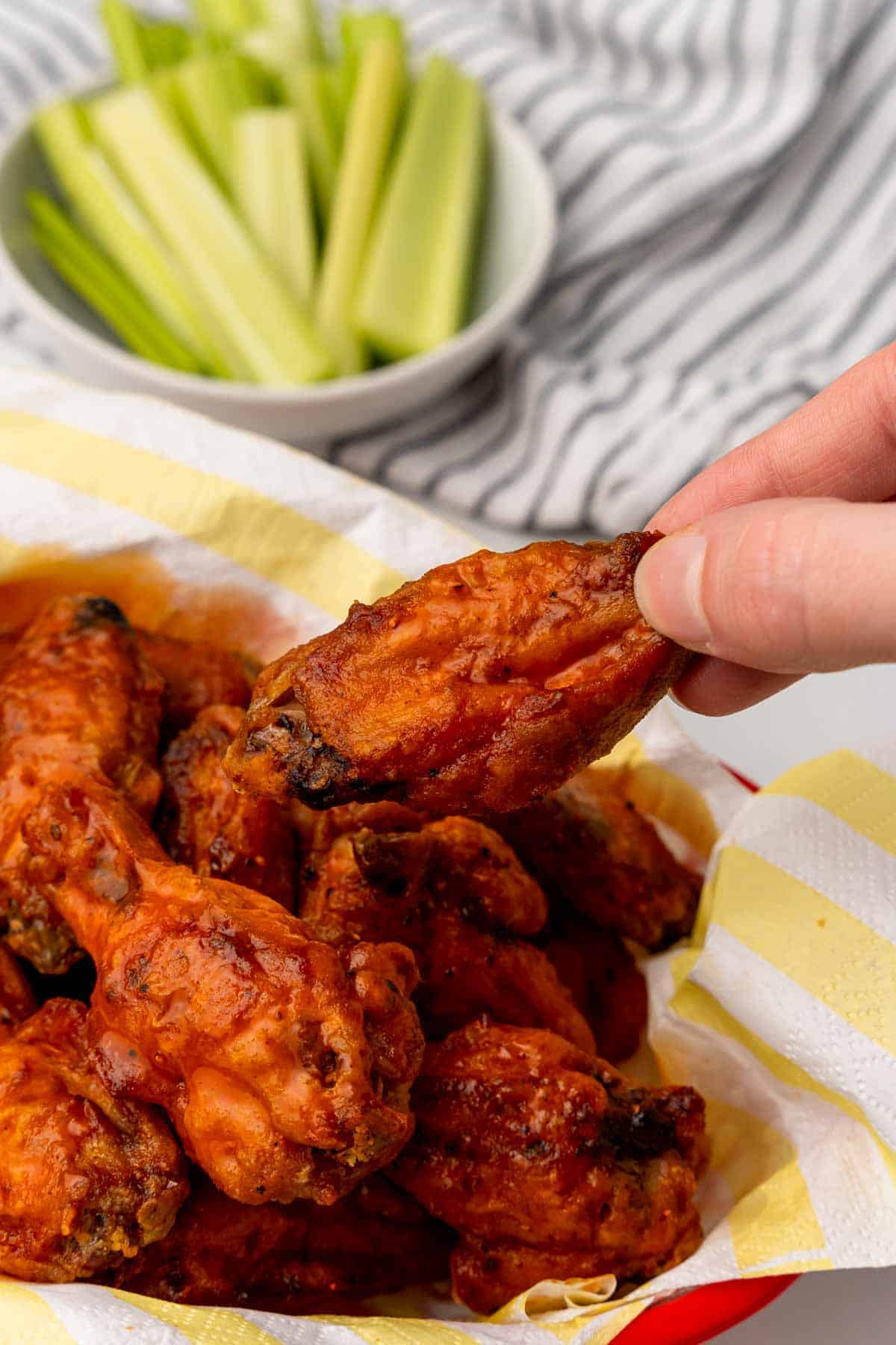 Hand taking a Carolina chicken wing from a plate of wings