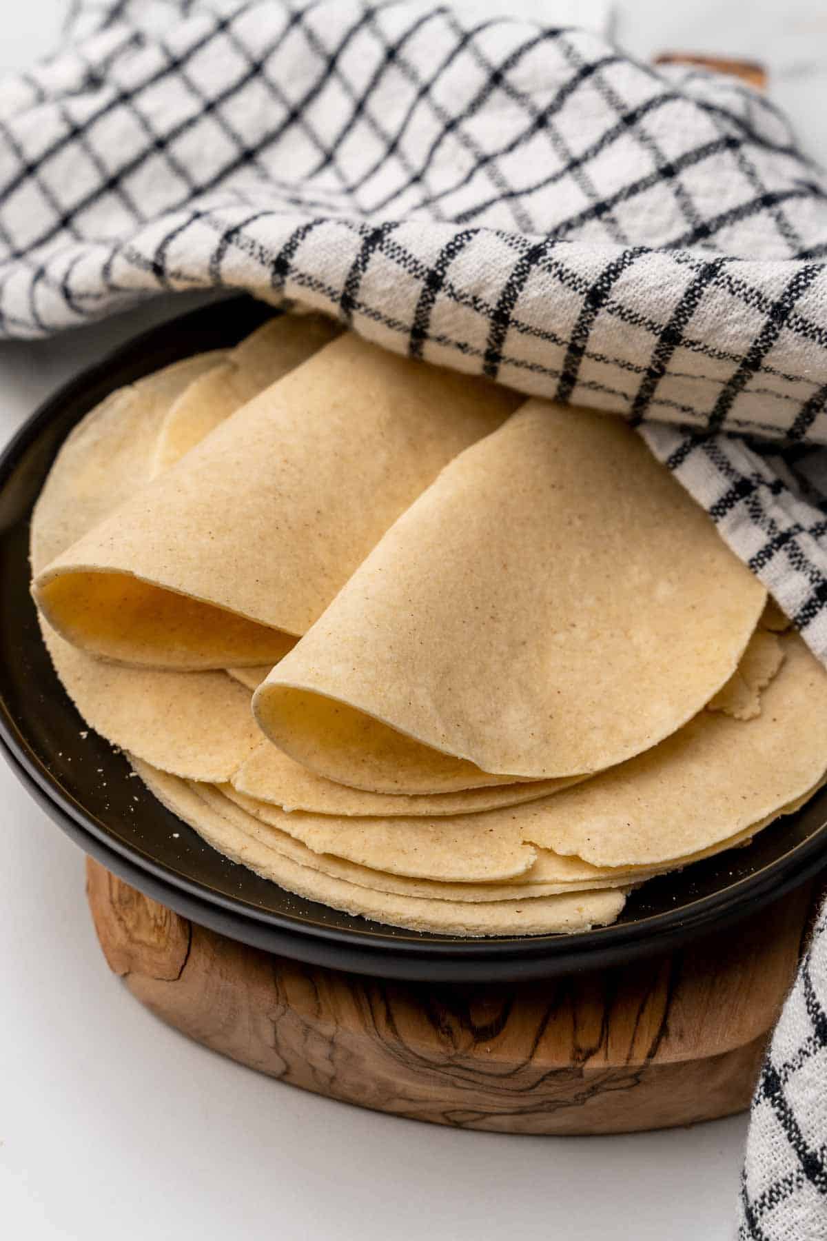 Plate of homemade tortillas partially covered with a dishtowel