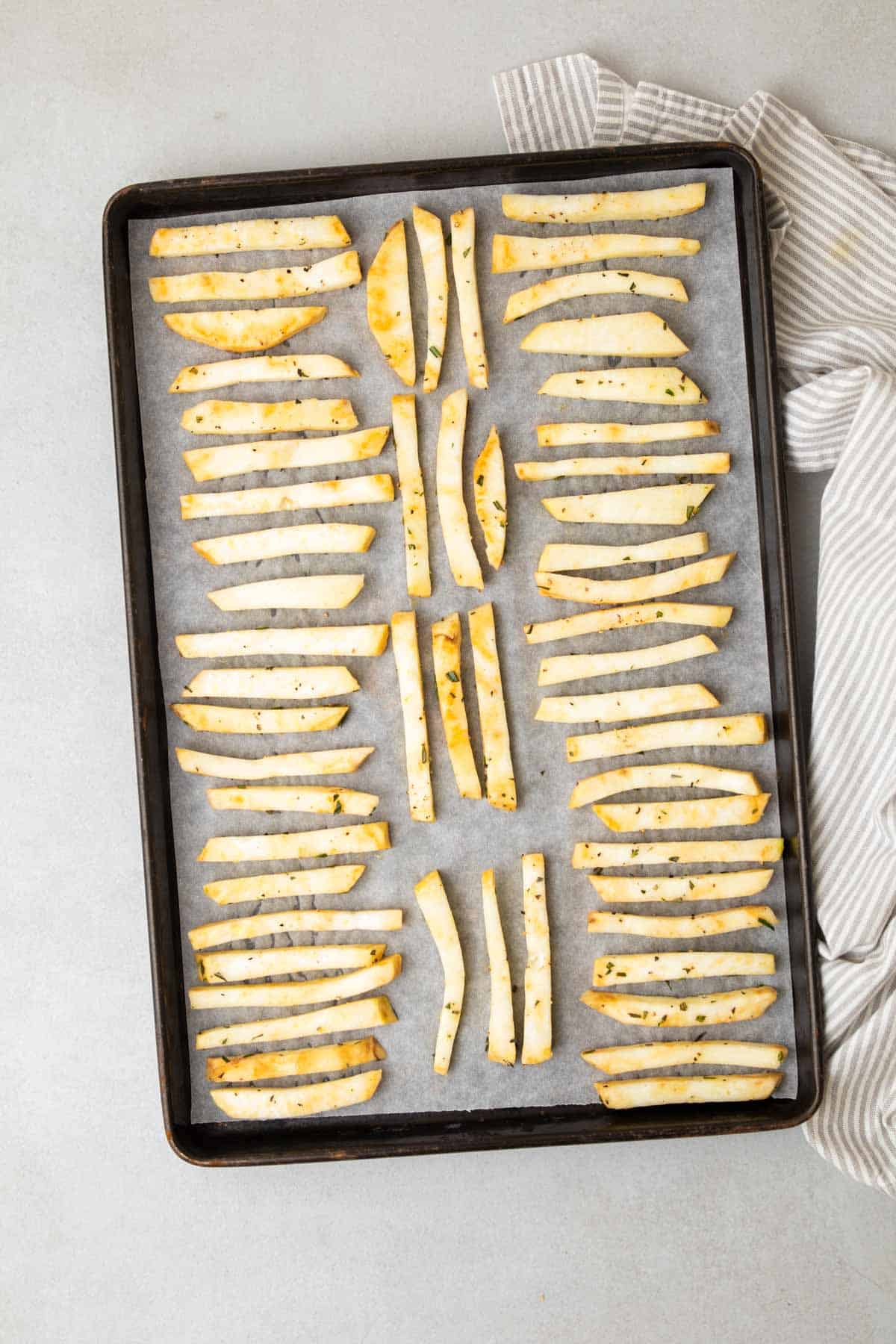 Fries in a single layer on a baking sheet, ready to go in the oven, as seen from above