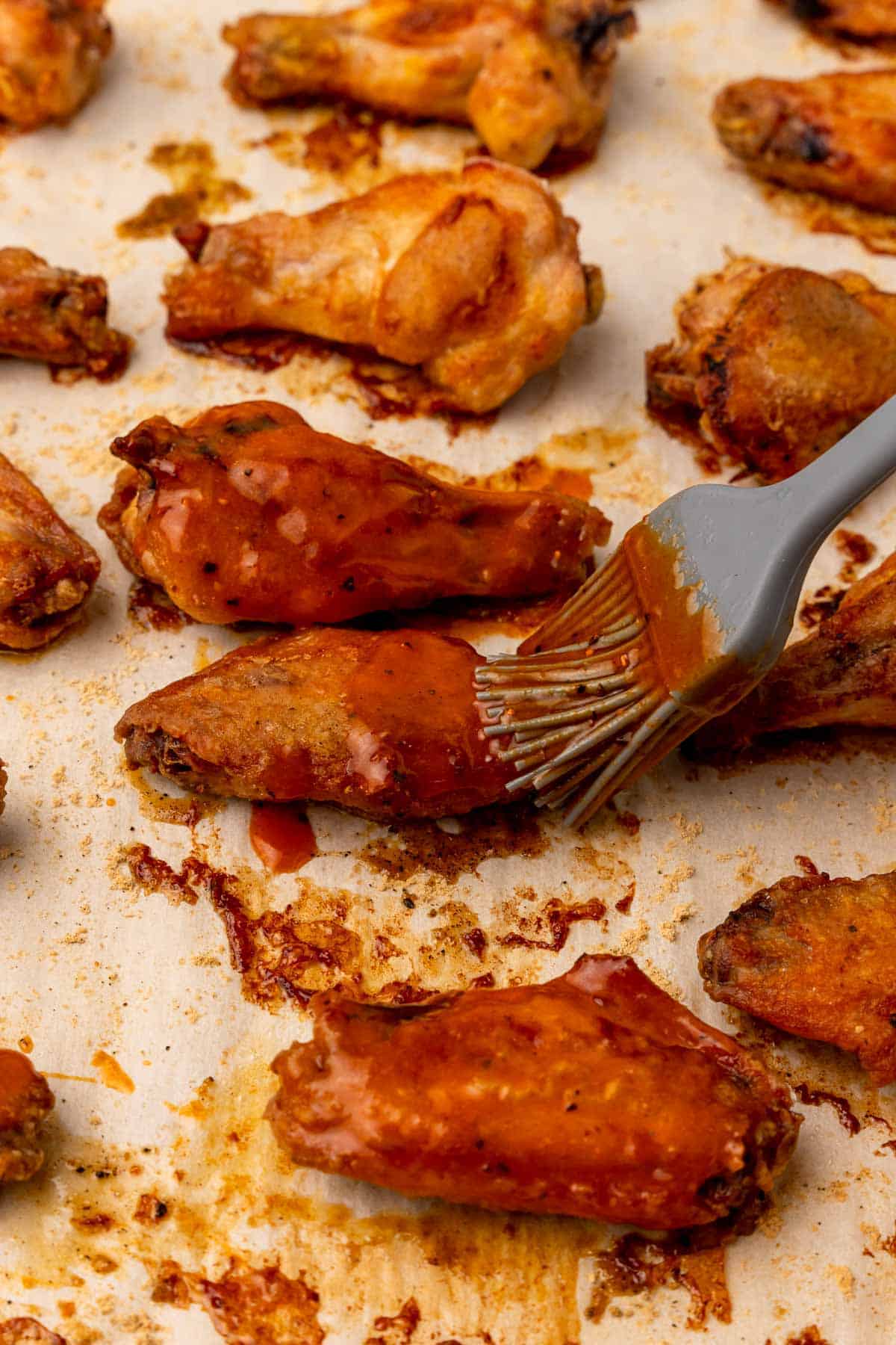 Brush coating the cooked chicken wings with sauce